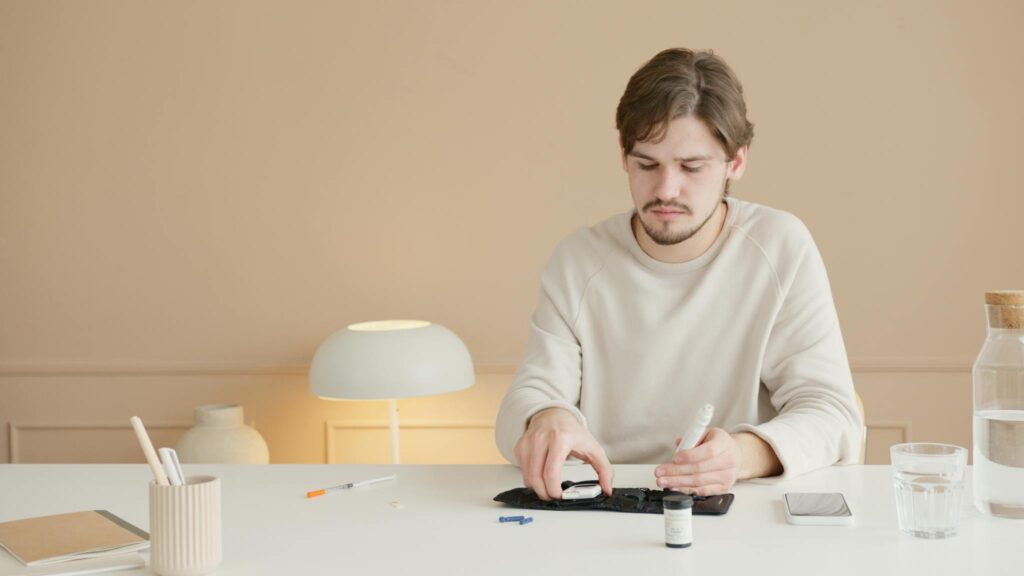 Young man checks blood glucose with a glucometer at home. Diabetes care and monitoring.
